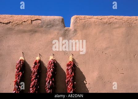Large chili ristras on adobe wall at the entrance to the Martinez Hacienda circa 1804 Taos New Mexico Stock Photo