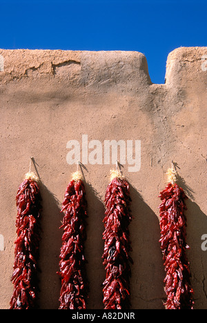 Large chili ristras on adobe wall at the entrance to the Martinez Hacienda circa 1804 Taos New Mexico Stock Photo