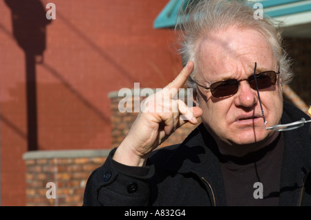 Angry old man in black and sun glasses with finger gesture Stock Photo