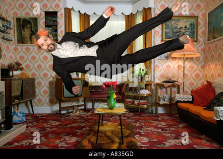 Airborne man dressed in a suit falling horizontally inside a living room Stock Photo