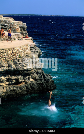 Teenage boy jumps and dives off into a sea Beach or Cala Brut Minorca Balearis islands Spain Stock Photo