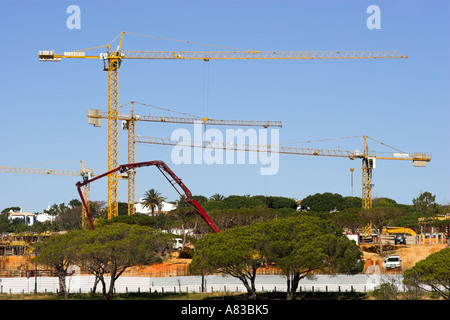 Tall cranes on a building site constructing new homes on a  development on the Algarve in Portugal. Stock Photo