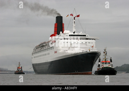 Tugs and Queen Mary II on Elbe river leaving Hamburg, Germany Stock Photo