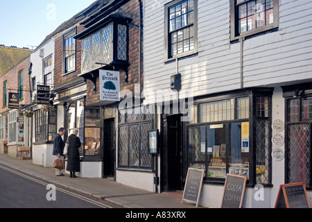 Man and woman window shopping in antique book store amidst terrace of shops, Lion Street, Rye, Sussex, UK Stock Photo