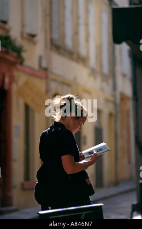 France. South.  Provence. Arles.   Young tourist studying her guide book in the old centre of Arles. Stock Photo