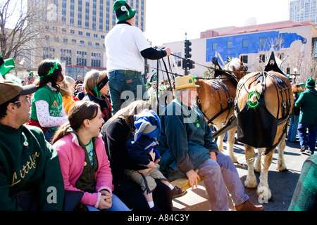 Team of horses wearing manure bags pulling wagon of Irish celebrators. St Patrick's Day Parade St Paul Minnesota USA Stock Photo