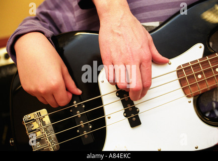 Teacher shows a boy how to play base during a lesson in music in school Stock Photo