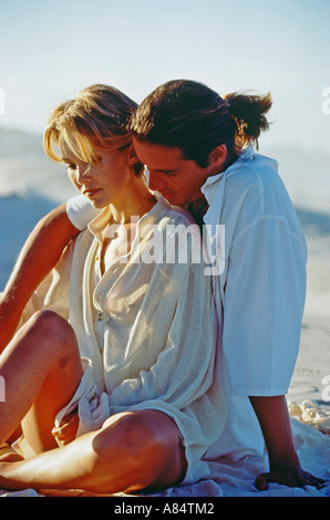 Young romantic couple sitting on a beach. Stock Photo