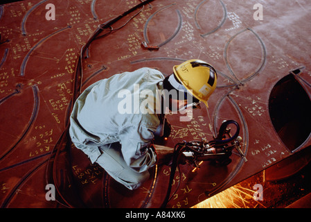 Singapore. Ship building industry. Overhead view of a man working cutting plate steel sections. Stock Photo