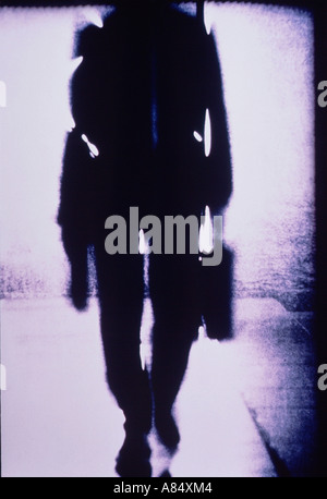 Indoor, shoulders down close-up impression silhouette of man with briefcase walking towards camera. Stock Photo