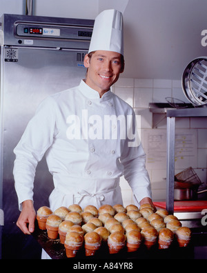 Chef in hotel kitchen holding tray of freshly baked brioche buns. Stock Photo