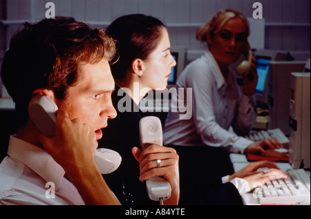 Call centre telephone operators with computer monitor screens at night. Stock Photo