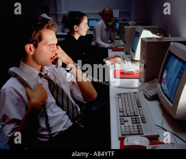 Call centre telephone operators with computer monitor screens at night. Stock Photo