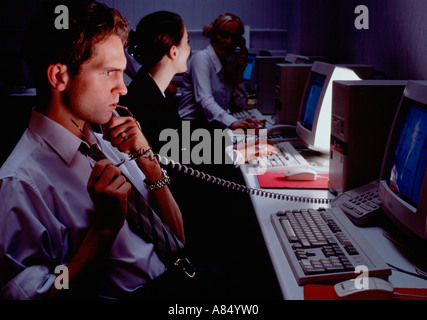 Call centre telephone operators with computer monitor screens at night. Stock Photo