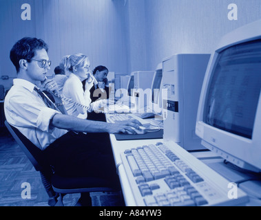 Call center telephone operators. Man using telephone whilst referring to computer screen.  Other operators in background. Stock Photo