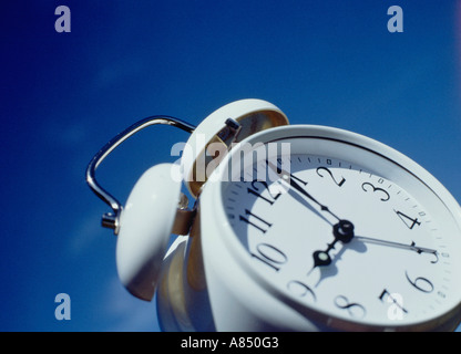 Concept image of white, traditional alarm clock against blue sky. Stock Photo