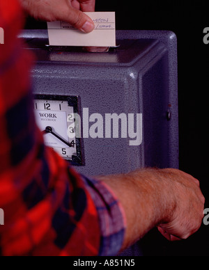 Close up of male factory worker clocking on with workplace time clock. Stock Photo
