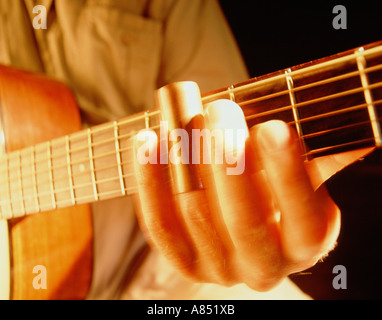 Close-up of man playing guitar.  Hand using finger slide on acoustic guitar neck. Stock Photo
