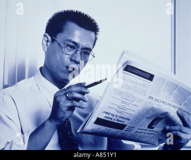 Young Chinese man studying newspaper. Stock Photo