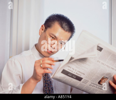 Indoor close-up of Chinese man studying newspaper. Stock Photo
