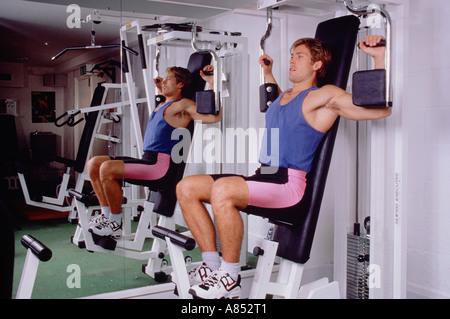Young man exercising using gymnasium equipment. Stock Photo