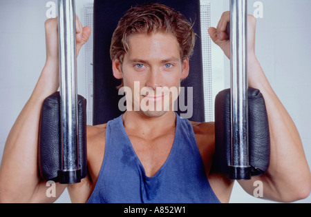 Indoor portrait of young man using exercise equipment in gymnasium. Stock Photo