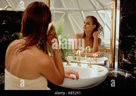 Young woman in bathroom. Combing hair in front of mirror Stock Photo