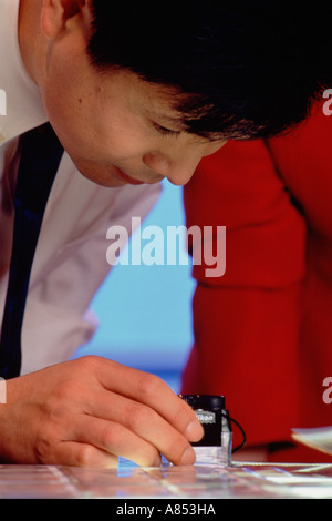 Closeup of man with magnifying loup working in office. Stock Photo