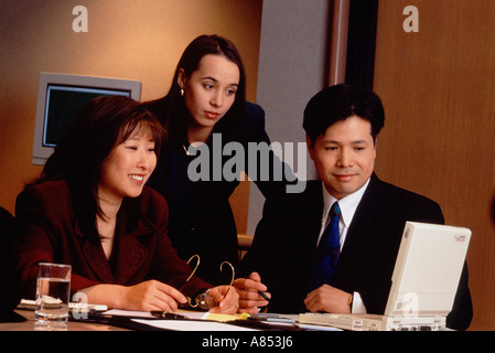 Three business people working in office with laptop computer. Stock Photo