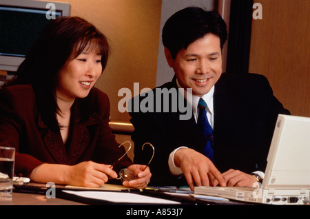 Indoor close-up of man and woman in office working with laptop computer. Stock Photo