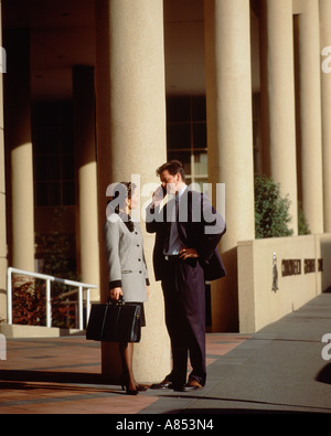 Young business man and woman standing outside city buildings. Stock Photo