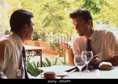 Two business men having lunch outdoors on restaurant terrace. Singapore. Stock Photo