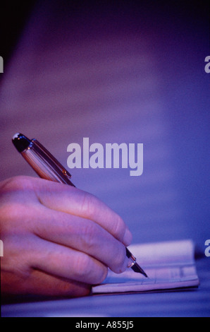 Indoor close-up of man's hand with pen cheque signing. Stock Photo