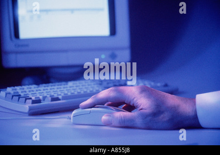 Close up of hand on computer mouse with monitor screen. Stock Photo