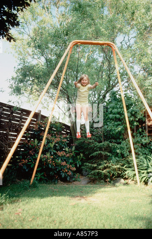 Child girl playing on garden swing Stock Photo