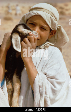 Morocco. Outdoor portrait of local child holding baby goat. Stock Photo