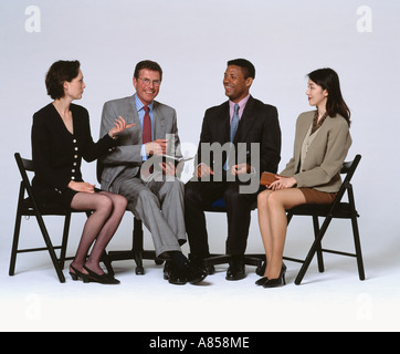 Indoor studio full length image of four seated people talking to each other. Stock Photo