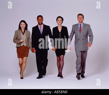 Studio image of a team of four people.  Two men and two women wearing business suits and walking towards camera. Stock Photo