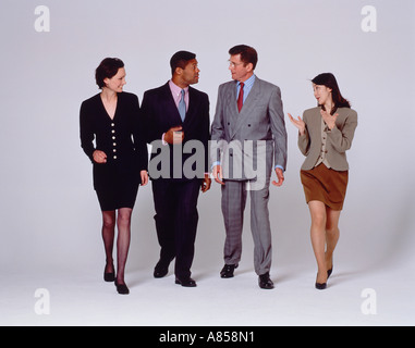 Indoor studio full length image of four walking people talking to each other. Stock Photo