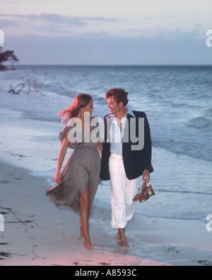 couple walking on beach at sunset Stock Photo