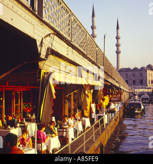 People sitting at an outdoor area of a restaurant under the famous Galata Bridge across the Bosphorus Istanbul Turkey Stock Photo