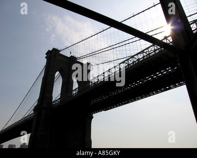 Sun setting behind silhouette of Brooklyn Bridge, New York City America USA Stock Photo