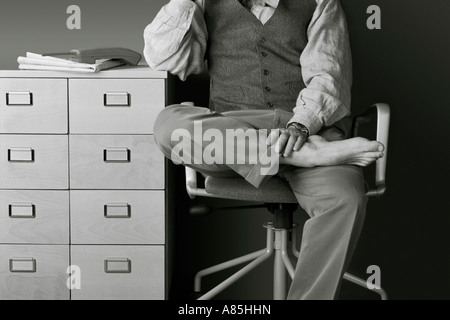 BUSINESSMAN SITTING ON CHAIR, RESTING AND THINKING IN THE OFFICE Stock Photo