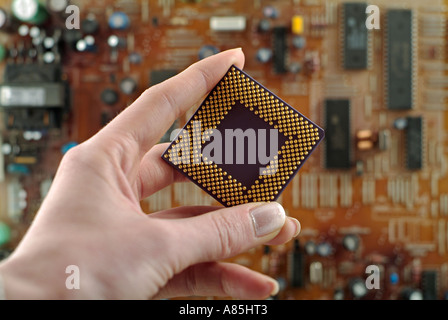 Hand Holding a Computer Processor Against a Background of a Circuit Board Stock Photo