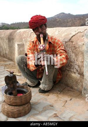 A traditional snake charmer hypnotizing a rattlesnake by playing an instrument called Pungi in Amer near Jaipur, Rajasthan, India. Stock Photo