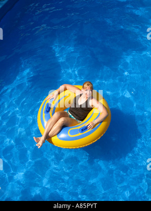 Young woman on inflatable tube in a pool. Stock Photo