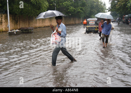 Indian people walking through streets flooded by monsoon rains in Bombay Mumbai India Stock Photo