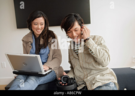 Woman working on laptop, man talking on phone Stock Photo