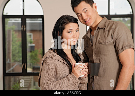 Young couple holding cups, portrait Stock Photo
