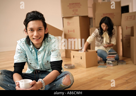 Young man holding cup while woman looking in the box, front view Stock Photo